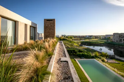 piscina moderna rodeada de deck y vegetación frondosa — proyecto Gray Rock, por BAS Y GARCIA , en Escobar